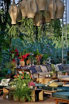 an outdoor living area with lots of plants and hanging baskets on the ceiling above it