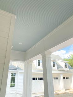 a white house with three large pillars and two garages