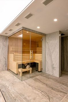 an indoor sauna room with glass walls and marble flooring