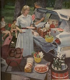 a woman standing in front of a picnic table filled with food next to a car