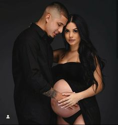 a man and woman are posing for a photo with their pregnant belly in front of them