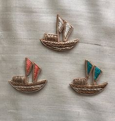 three small sailboats are sitting on a white cloth