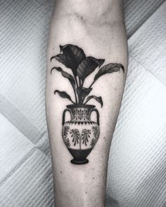 a black and white photo of a vase with a plant in it on the leg