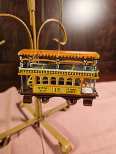 a miniature model of a yellow trolley on a pink tablecloth with gold trimming