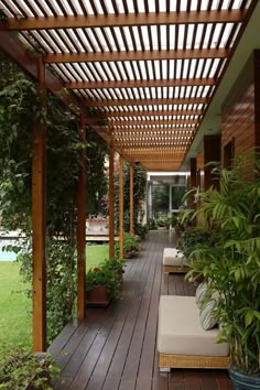 an outdoor covered patio with wooden flooring and potted plants on either side of the walkway