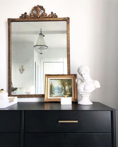 a dresser with a mirror and vase on top of it next to a busturine