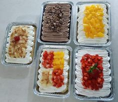 four trays filled with different types of fruit and chocolate ice cream treats on top of a table