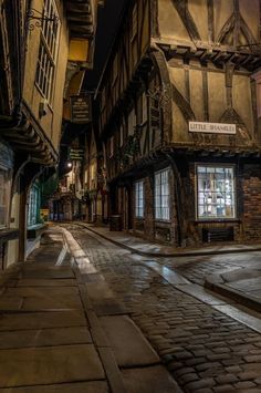 an old european street at night with cobblestones and half - timbered buildings