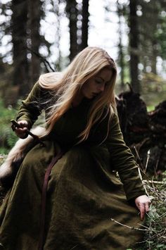 a woman sitting in the woods with long blonde hair