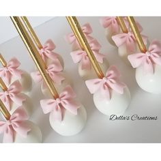 pink and white cake pops with bows on them are ready to be served for guests