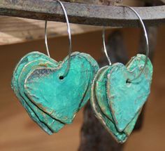 two turquoise heart shaped earrings hanging from a tree branch