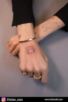 two people holding hands with tattoos on their arms and one has a small bear tattoo on the wrist