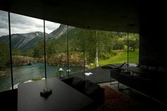 a living room filled with furniture next to a window covered in glass overlooking a river