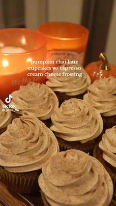 cupcakes with frosting sitting on a tray next to candles and pumpkins