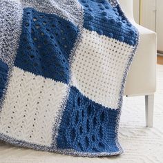 a blue and white crocheted blanket sitting on top of a couch next to a chair