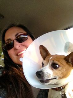 a woman is holding a dog with a cone on it's head