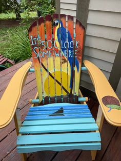 a blue and yellow wooden chair with a book on it's back end sitting on a deck