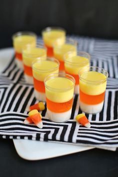 small glasses filled with orange and white jello on a black and white table cloth