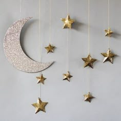 the moon and stars are hanging from the string on the wall, which is decorated with gold glitter