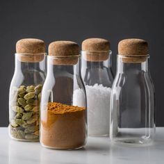 three glass bottles filled with different types of spices