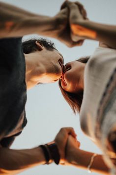 two people kissing each other while standing next to each other with their hands in the air