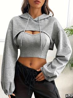 a woman wearing a grey crop top and black pants with her hands on her hips