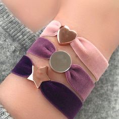 a close up of a person's arm wearing purple and silver bracelets with hearts on them