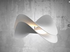 a white light hanging from the ceiling in front of a concrete wall with an abstract design