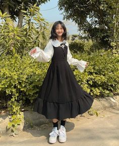 a woman in a black and white dress posing for the camera with her arms outstretched