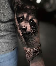 a man's arm with a raccoon tattoo on it