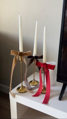 three candles with ribbons tied around them are sitting on a table next to a television