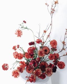 a white vase filled with lots of red flowers