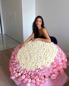 a woman sitting on top of a giant cake covered in flowers and pink ribboning