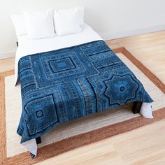 a bed with a blue blanket on top of it next to pillows and rugs