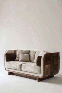 a white couch with pillows on it in front of a beige wall and wooden frame