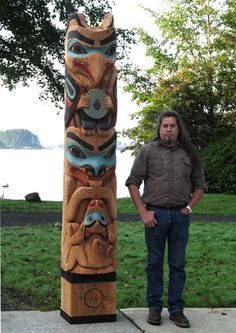 a man standing in front of a totem pole