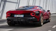 the rear end of a red sports car driving on a road