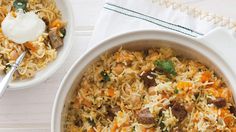 two white bowls filled with rice and meat on top of a table next to a napkin