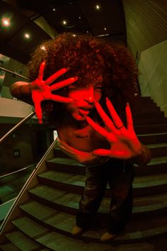 a woman holding her hands up in front of her face with red light painted on it