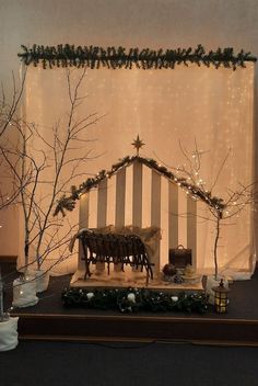 a nativity scene is displayed in front of a window with christmas lights on it