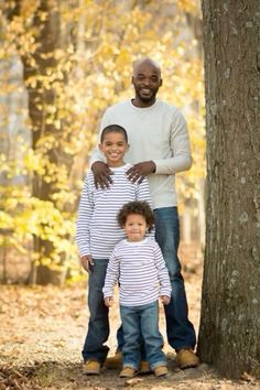 an adult and two children standing next to a tree