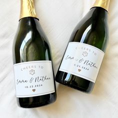 two bottles of wine sitting next to each other on a white sheet with gold trim