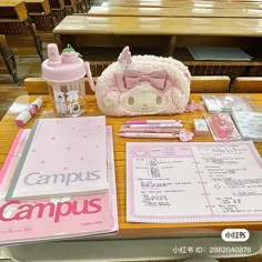 a table with pink items on it in a school setting, including notebooks and pens