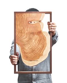 a man is holding up a wood cutout with an image of a person's face