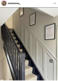 the stairs are painted white and have black railings on each side, along with framed pictures above them