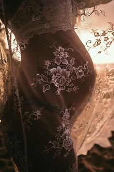 a pregnant woman's belly is covered in lacy fabric and lace, with flowers on it