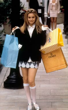 a woman is walking down the street with shopping bags in her hand and holding a bag