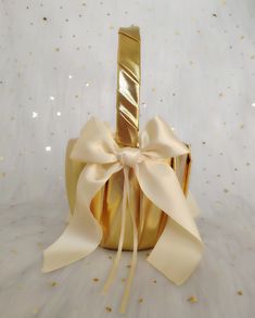 a gold gift box with a white ribbon tied around it