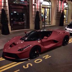 a red sports car is parked on the street in front of a building at night