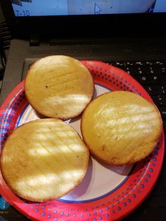 three cookies sitting on top of a plate next to a laptop computer and keyboard in front of it